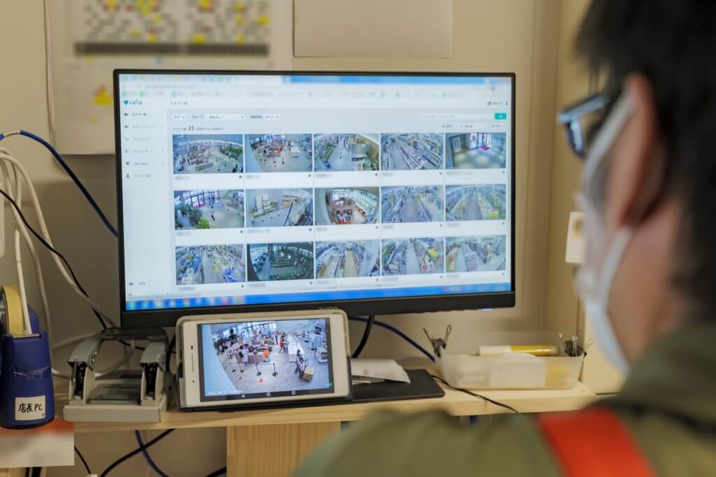 PCで店内の防犯カメラ映像を確認する店長